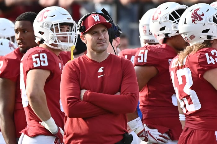 Washington State head coach Jake Dickert standing on the sidelines with his team.